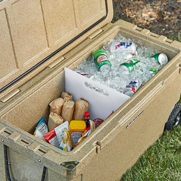 A CaterGator divider for a cooler with food and drinks in it on a table outdoors.