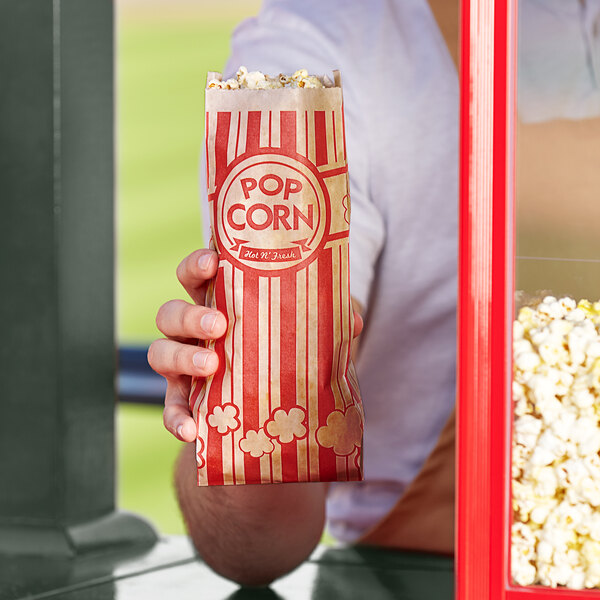 A person holding a Carnival King Kraft popcorn bag filled with popcorn.