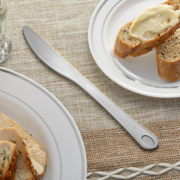 A Visions heavy weight silver plastic knife on a plate with food and butter on it.