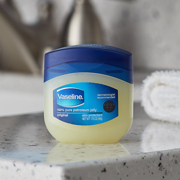A plastic jar of Vaseline petroleum jelly with a blue lid on a counter.