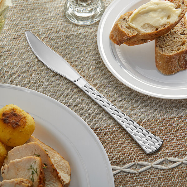 A piece of bread with butter on a plate with a Visions silver plastic knife.