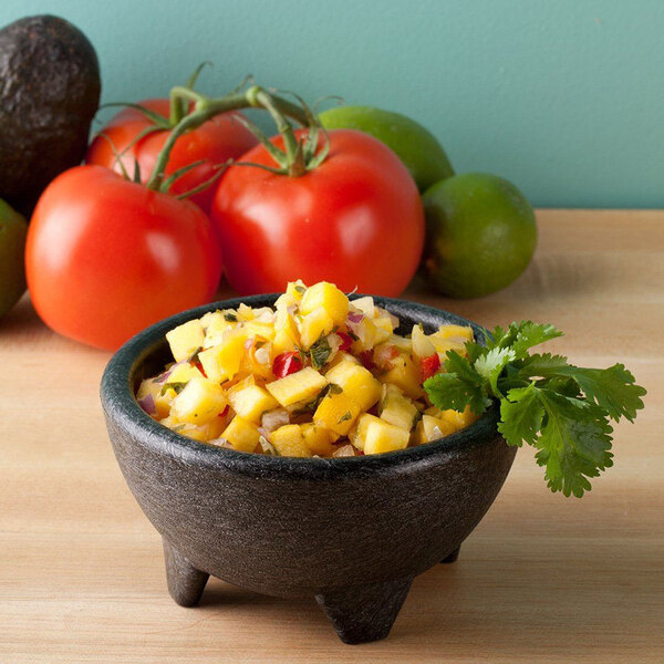 A charcoal polypropylene molcajete filled with salsa made with tomatoes and avocados.
