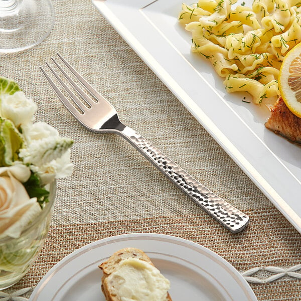 A plate of pasta with a Visions rose gold plastic fork on a table.