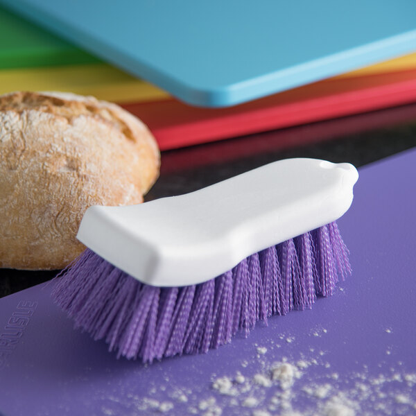 A white brush with a white handle on a purple cutting board.