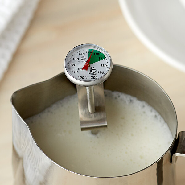 A Comark frothing thermometer in a metal pitcher of milk.