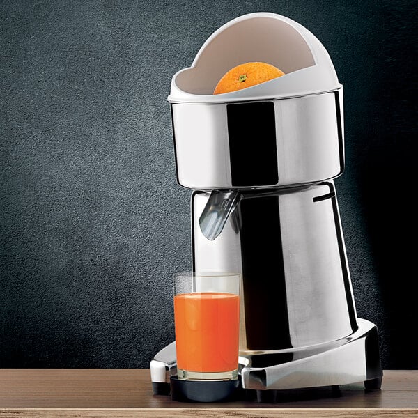A Ceado S98 citrus juicer on a table with a glass of orange juice.