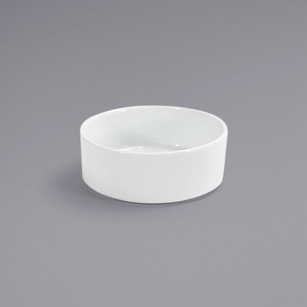 A Front of the House Soho bright white porcelain ramekin on a gray surface.