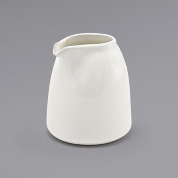 A Front of the House European white porcelain creamer with a white handle.