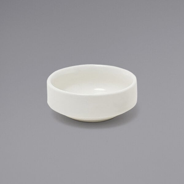 A Front of the House European white porcelain ramekin on a gray surface.