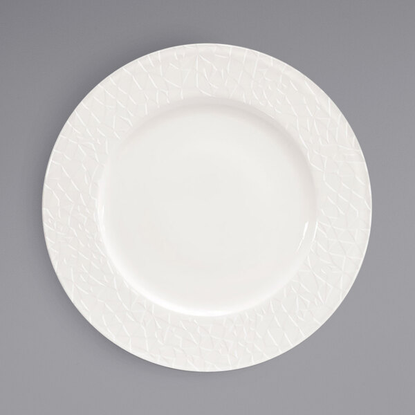 A white Front of the House Catalyst porcelain plate with a pattern on the rim.