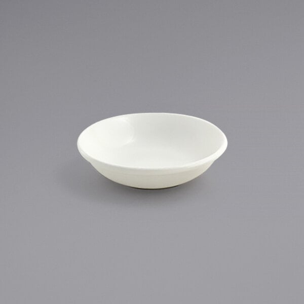 A Front of the House Catalyst European White Porcelain Sauce Dish on a gray surface.