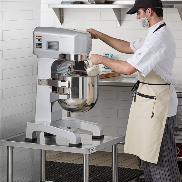 A man in a white shirt and apron using a Galaxy Planetary Stand Mixer.