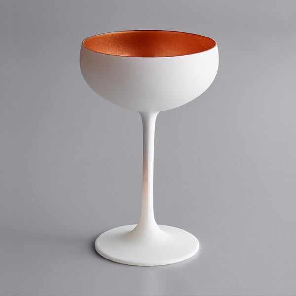 A Stolzle white wine glass with a copper rim and tall stem.