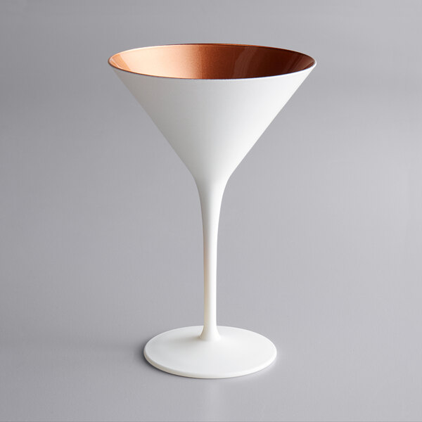 A matte white and copper Stolzle martini glass on a grey surface.