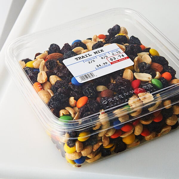 A plastic container of trail mix on a counter.