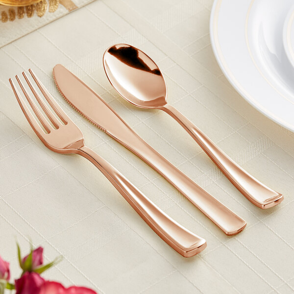A Visions rose gold plastic spoon and fork on a table.