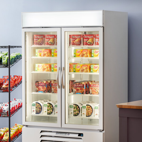 A Beverage-Air white glass door merchandiser with food on shelves.