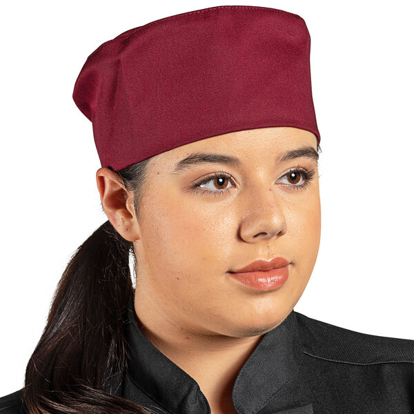 A woman in a Uncommon Burgundy chef's hat with a hook and loop closure on a counter in a professional kitchen.