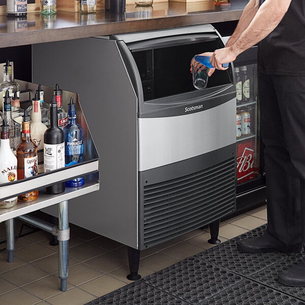 A person putting a glass into a Scotsman undercounter ice machine.