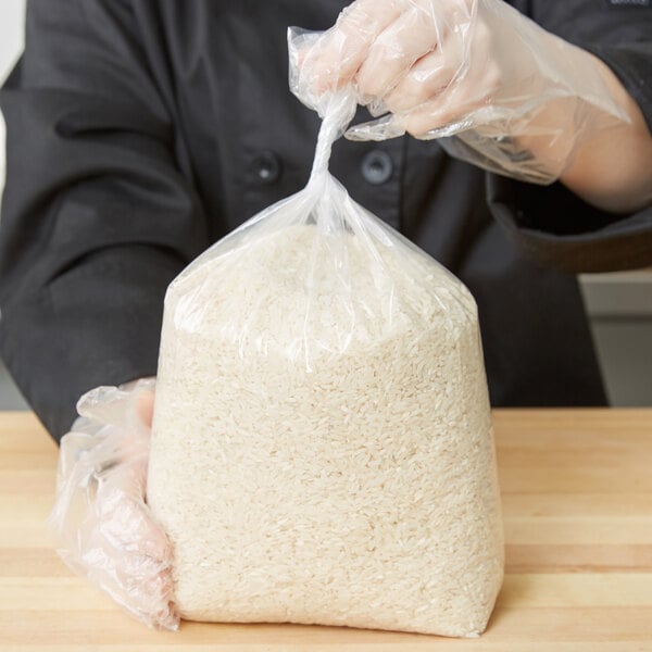 A person in a black coat holding a plastic bag of rice.