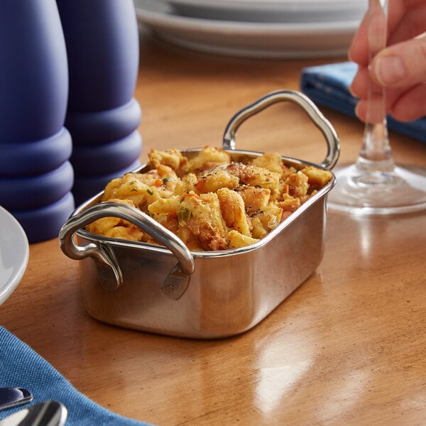 A Vollrath rectangular mini stainless steel roasting pan filled with food on a table.
