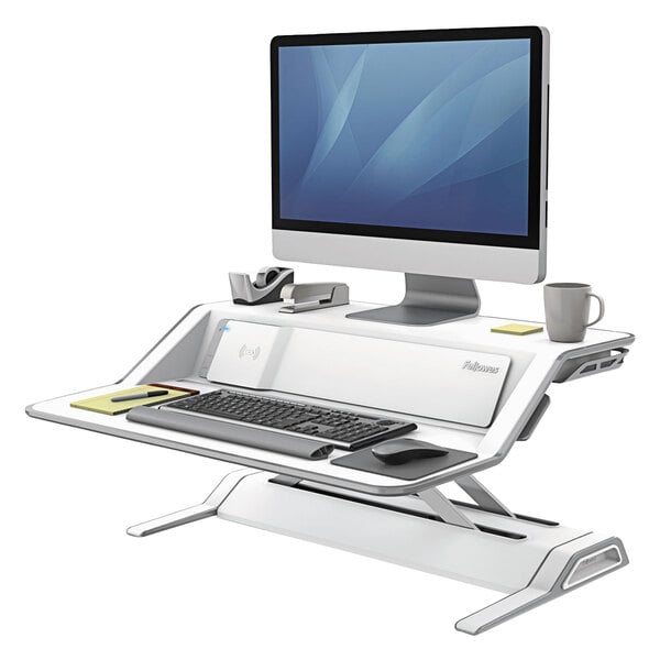 A Fellowes white sit-stand workstation with a keyboard and monitor on a desk.