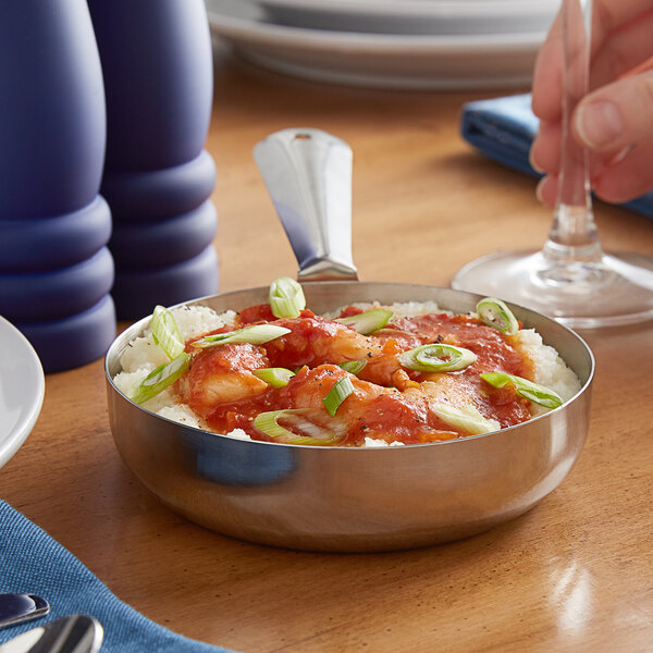 A hand holding a Vollrath mini stainless steel fry pan filled with rice, shrimp, and vegetables.