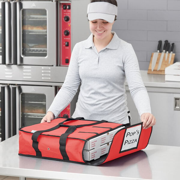 A woman holding a red Choice insulated pizza delivery bag with white pizza boxes inside.