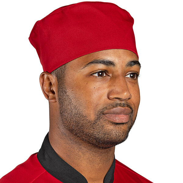 A man wearing a red Uncommon Chef skull cap in a professional kitchen.