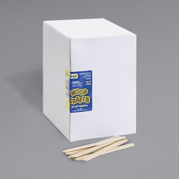 A white box with a blue label of Creativity Street natural wood craft sticks next to a few wooden sticks.