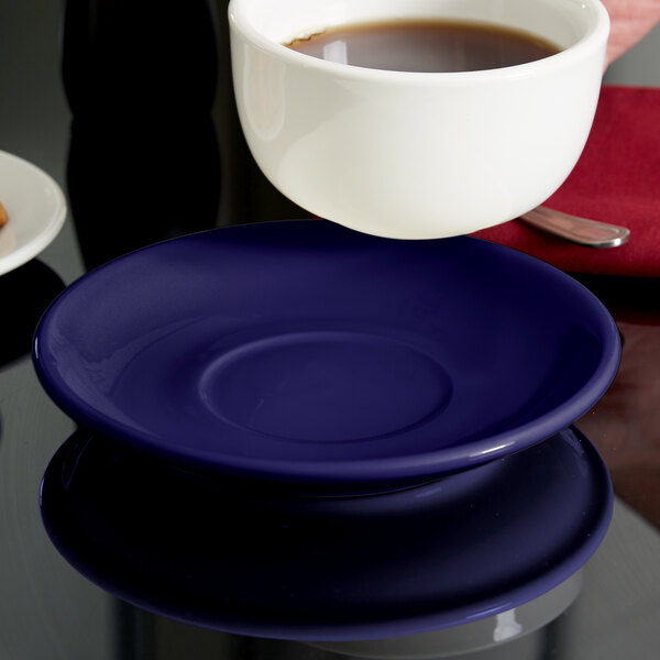 A cup of coffee on a Tuxton cobalt cappuccino saucer.