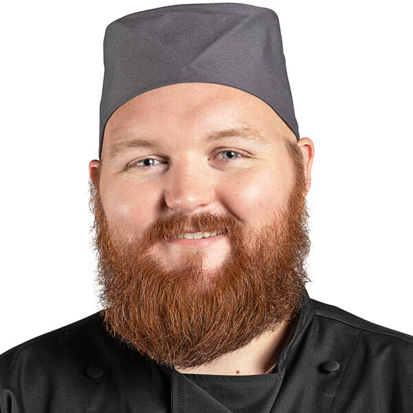 A bearded man wearing a Uncommon Chef slate gray chef skull cap with hook and loop closure.