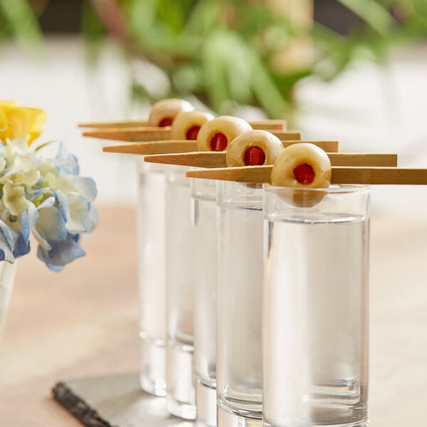 A group of shot glasses with stuffed queen olives on them.