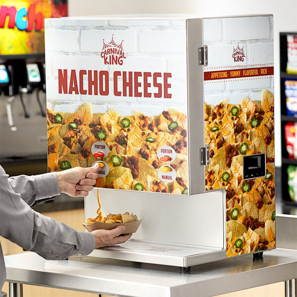 A man using a Carnival King dual peristaltic cheese dispenser to top nachos.