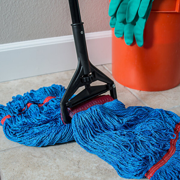 A Carlisle vinyl-coated metal mop handle with a plastic head on a mop on the floor.