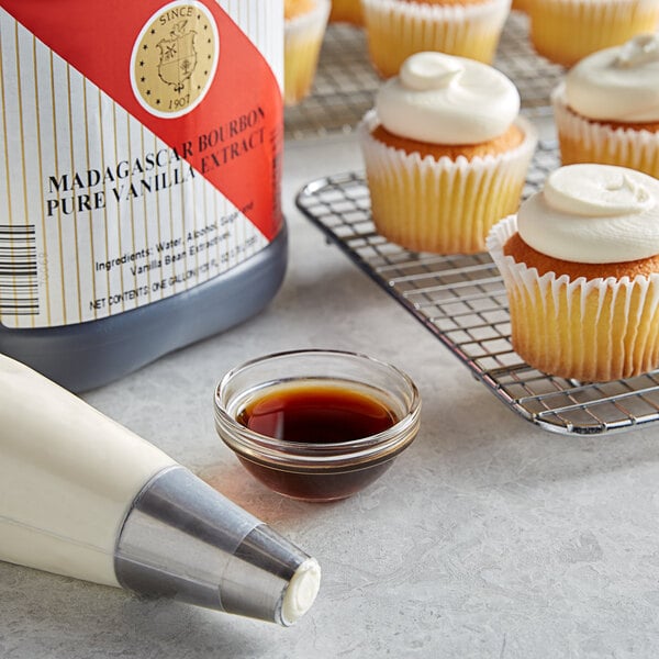 A cupcake with white frosting and a bottle of Nielsen-Massey Madagascar Bourbon Vanilla Extract next to it.