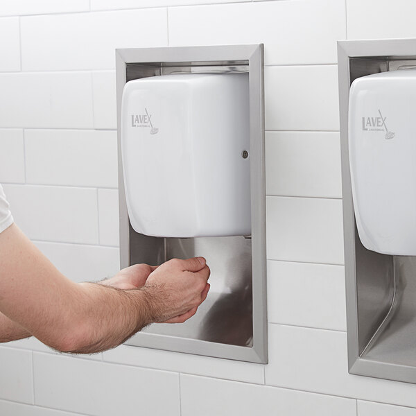 A man using a Lavex Stainless Steel ADA Compliant Recess Kit for a hand dryer in a bathroom.