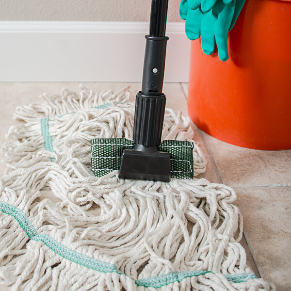 A Carlisle vinyl-coated metal mop handle with a plastic head next to a mop on the floor.