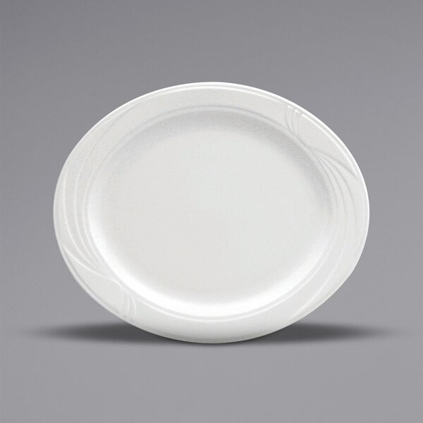 A close-up of a Oneida Buffalo Arcadia bright white porcelain oval platter with a curved edge and an embossed design.
