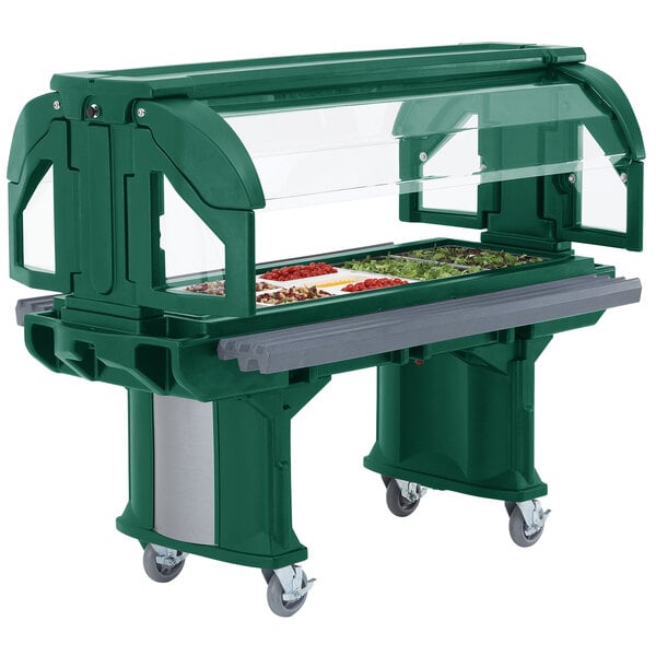 A green Cambro Versa food bar with wheels and a glass top on a table in a salad bar.