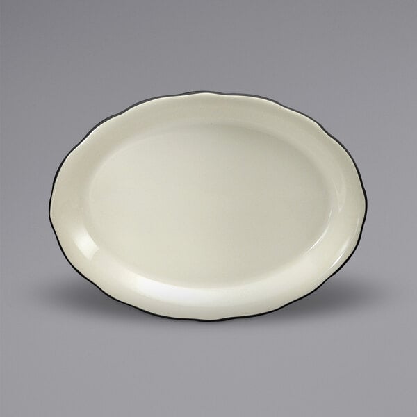 A white china oval platter with scalloped edges and black trim.