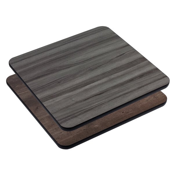 Two American Tables & Seating square wood laminate table tops with gray and brown panels stacked on them.