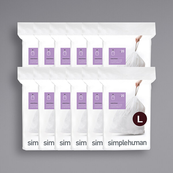 A person holding a white plastic bag with a purple and white label for simplehuman Code L trash can liners.
