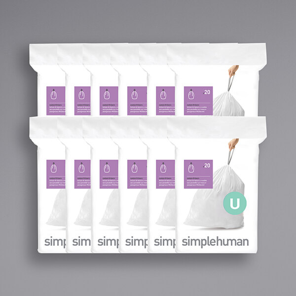 A person holding a white package of simplehuman trash can liners with a purple border.