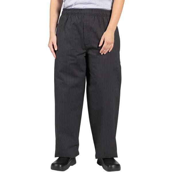 A woman wearing Uncommon Chef triple pinstripe chef pants with a grey shirt.
