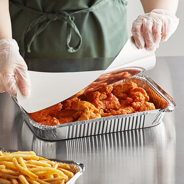 A person in gloves putting food in a Choice foil tray.