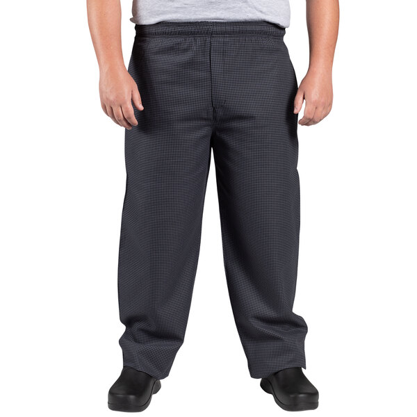 A man wearing Uncommon Chef black and gray houndstooth chef pants.
