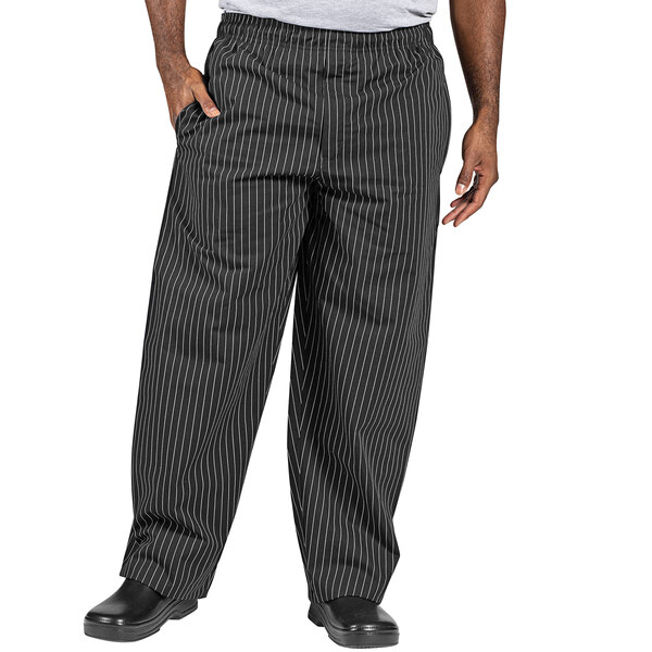 A person wearing Uncommon Chef black pants with white pinstripes.