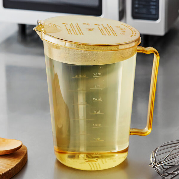 A Cambro amber measuring cup with a splatterproof cover on a white background.