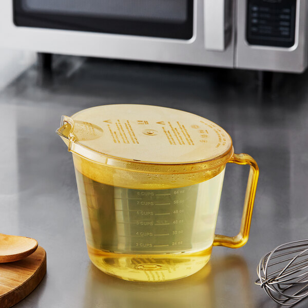 A Cambro amber measuring cup with liquid in it on a counter.